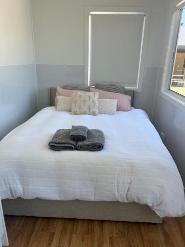 a bedroom with a bed with towels on it at Sweet Cute blue tiny home with Pool and 2 minute drive to the beach in Wollongong