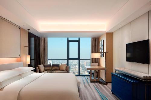 um quarto de hotel com uma cama grande e uma televisão de ecrã plano em Sheraton Zibo Hotel em Zibo