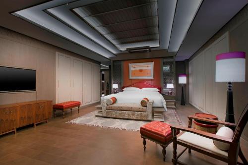 a bedroom with a bed and a flat screen tv at Sheraton Grand Xishuangbanna Hotel in Jinghong