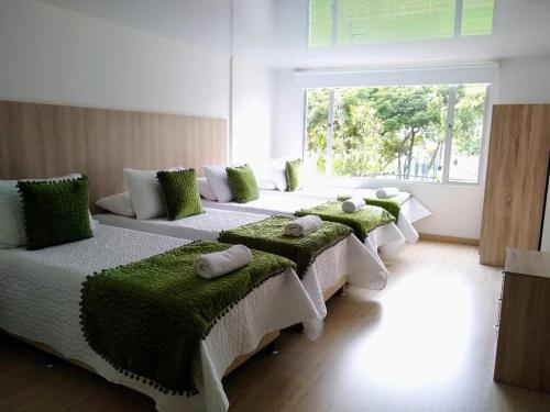 a room with four beds with green cushions on them at FEDERMAN PARK HOTEl in Bogotá