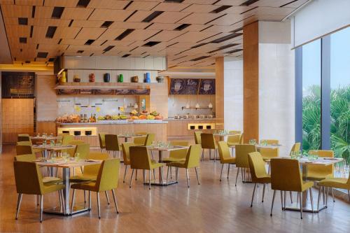 a dining room with tables and yellow chairs at Four Points by Sheraton Surabaya, Tunjungan Plaza in Surabaya