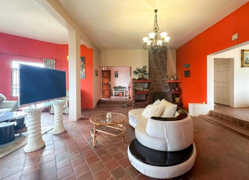 uma sala de estar com paredes cor de laranja e uma televisão em Tarkshay Hospitality em Densainagar