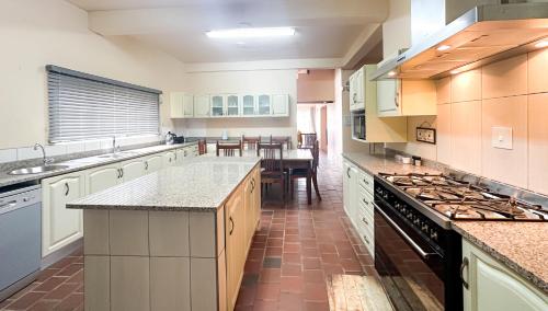 a large kitchen with white cabinets and a table at Tarkshay Hospitality in Densainagar