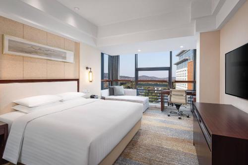 a hotel room with a large bed and a desk at Courtyard by Marriott Wuxi Lihu Lake in Wuxi
