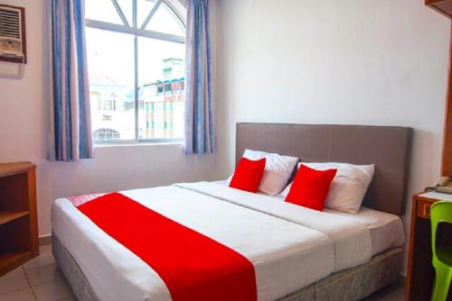 a bedroom with a red and white bed with a window at Hotel Kristal, Keningau in Keningau