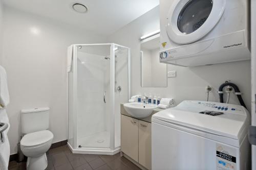 La salle de bains blanche est pourvue de toilettes et d'un lavabo. dans l'établissement Proximity Apartments Manukau / Auckland Airport, à Auckland
