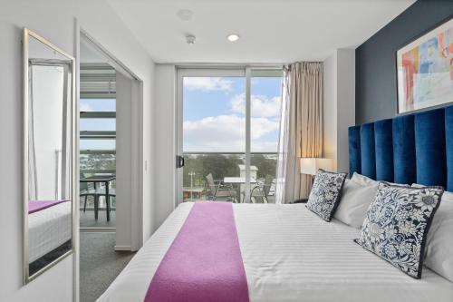 ein Schlafzimmer mit großem Bett und Balkon in der Unterkunft Proximity Apartments Manukau / Auckland Airport in Auckland