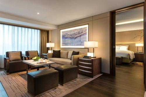 Habitación de hotel con cama y sala de estar. en Marriott Executive Apartments Tianjin TEDA, en Binhai