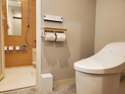 uma casa de banho com um WC branco e um espelho. em Trust Hotel em Hiroshima
