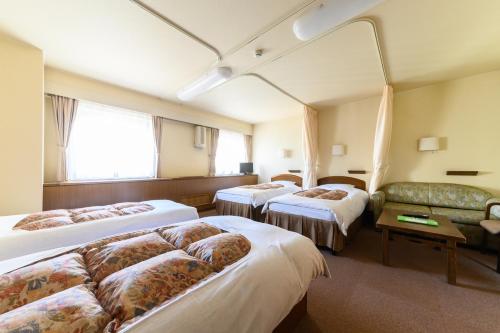um quarto de hotel com três camas e um sofá em Sapporo International Youth Hostel em Sapporo