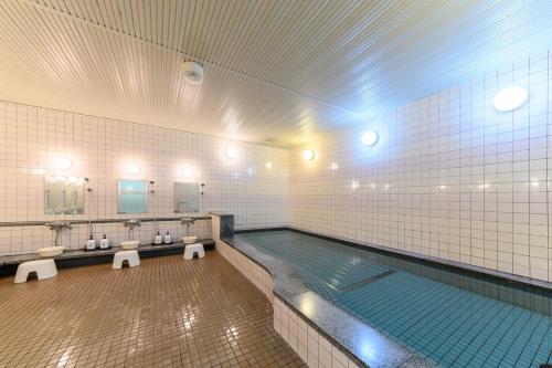 a swimming pool in a bathroom with sinks and mirrors at Sapporo International Youth Hostel in Sapporo