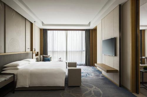 蘇州市にあるSuzhou Marriott Hotel Taihu Lakeのベッドとテレビが備わるホテルルームです。