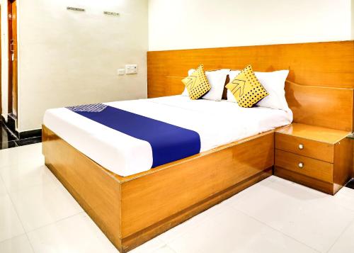 a bedroom with a bed with a wooden headboard at SPOT ON Srinivasa Residency in Tirupati