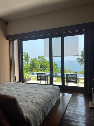 a bedroom with a bed and a large window at The Puncak Lombok in Senggigi 