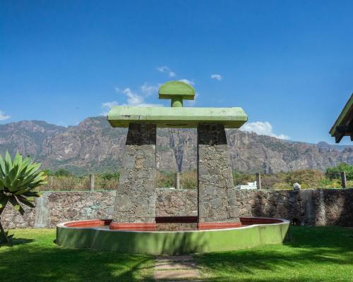 a monument in the grass with mountains in the background at Villas Mexiko in Tepoztlán