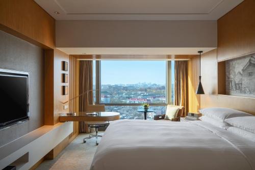Habitación de hotel con cama, escritorio y TV. en Renaissance Beijing Wangfujing Hotel, en Beijing