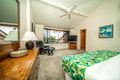 a bedroom with a bed and a desk with a fan at Kaanapali Royal B303 in Lahaina