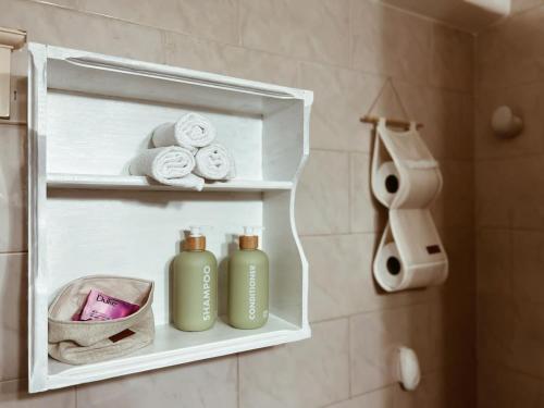 a bathroom with two green bottles and towels on a shelf at Casa Arrayanes Tempo in Esquel