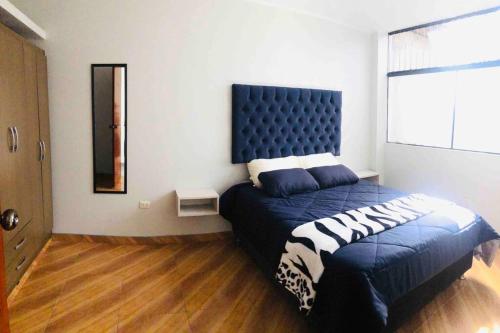 1 dormitorio con cama azul y ventana grande en Departamento moderno cerca del aeropuerto., en Lima