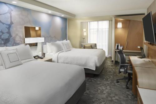 a hotel room with two beds and a desk at Courtyard by Marriott Oshawa in Oshawa