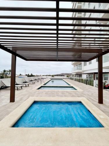 a swimming pool on a building with a large roof at Chipipe Salinas in Salinas
