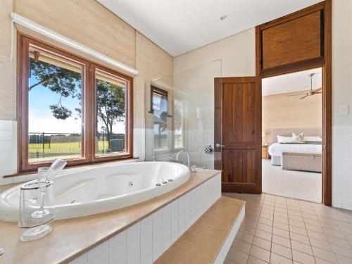 a large bathroom with a tub and a bedroom at Forest Rise Chalets and Lodge in Metricup