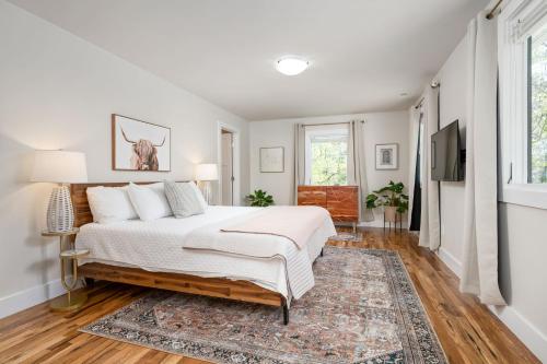 een witte slaapkamer met een bed en een televisie bij Luxury mountain oasis, hot tub & 15 mins to DT AVL in Juno