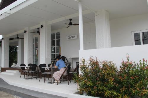 a person sitting at a table on the porch of a house at Luckswan Boutique Chiang Rai - SHA Extra Plus in Chiang Rai
