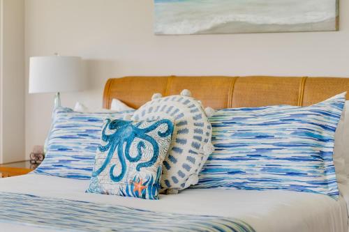 Una cama con almohadas azules y blancas. en Kapalua Bay Villas 36G5, en Kahana