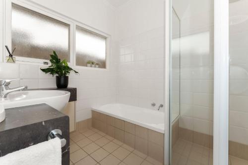 a white bathroom with a tub and a sink at Belle Escapes - Beauty at the Beach in Glenelg