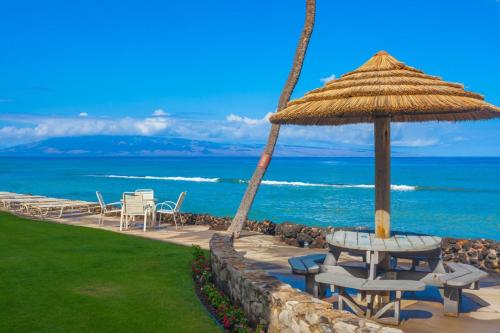 a table and chairs with an umbrella and the ocean at Kaleialoha 409 · KA 409 OceanFront 1BD Condo w Ocean Views Pool in Kahana