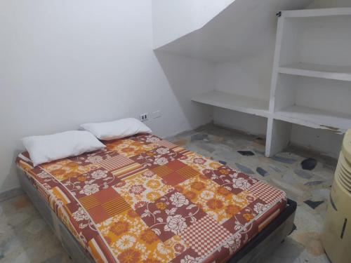 a small bedroom with a bed and a shelf at Apartamento Villa Rocio in Yopal