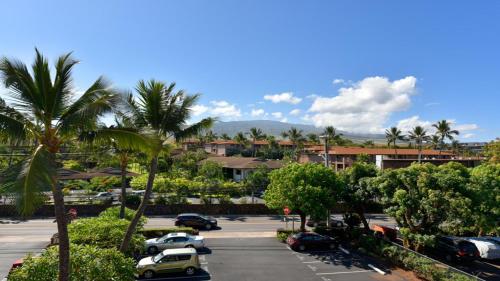 a parking lot with parked cars and palm trees at Kaleialoha 401 · KA 401 Spacious Studio w Mountain View Pool AC in Kahana