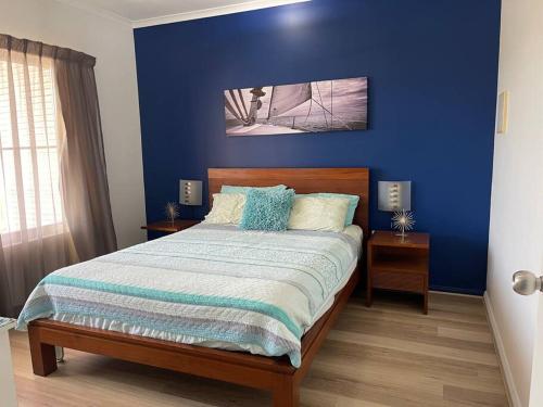 um quarto com uma parede azul e uma cama em Marina Views Apartment Cullen Bay em Larrakeyah