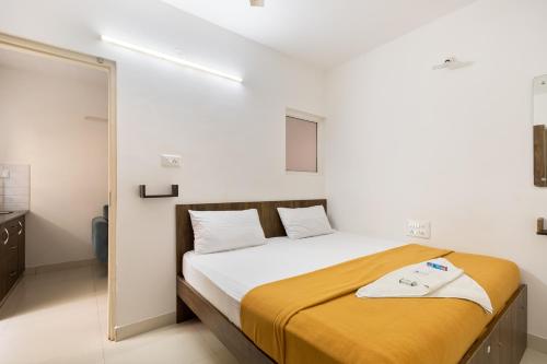 um quarto com uma cama grande e um cobertor amarelo em StayhomeStays Prime em Bangalore