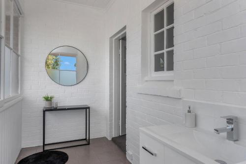 La salle de bains blanche est pourvue d'un lavabo et d'un miroir. dans l'établissement Best on Letitia Central spacious stylish sleeps 6, à Hobart