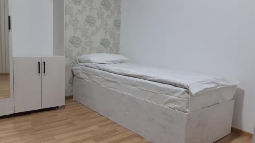 1 cama en una habitación junto a un armario blanco en Гостиничный дом Эко, en Karakol