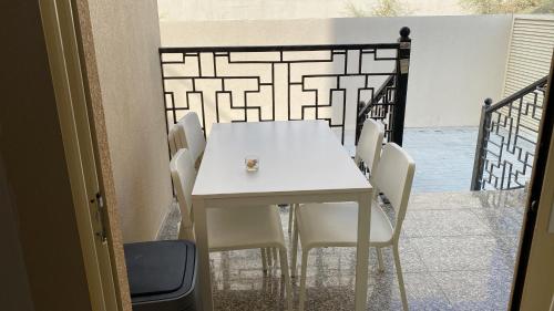 Your apartment near Airport في أبوظبي: طاولة بيضاء وكراسي على شرفة