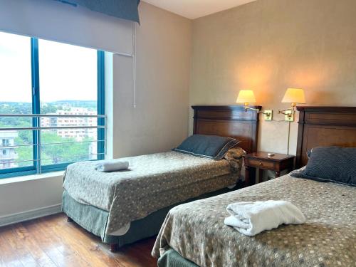 Lujoso departamento en la mejor ubicación de la ciudad de Mendoza con vista a la montaña في ميندوزا: غرفة فندقية بسريرين ونافذة كبيرة