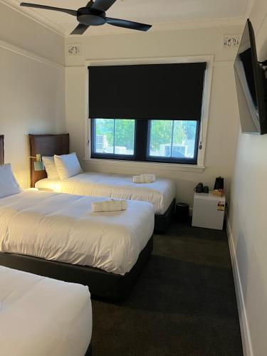 a bedroom with two beds and a large window at Sportsmens Club Hotel in Wagga Wagga