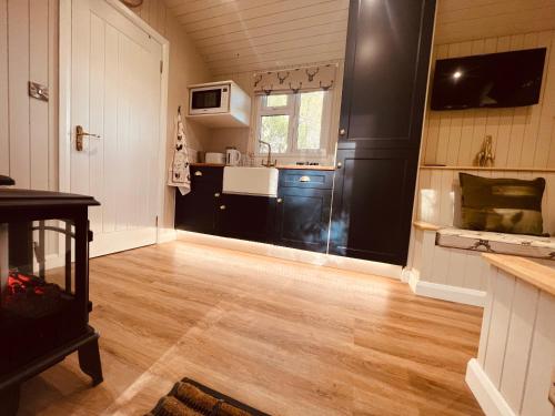 kuchnia z czarnymi szafkami i drewnianą podłogą w obiekcie Bodos’ Shepards Hut w mieście Durham
