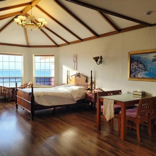 a bedroom with a bed and a table and chairs at Sunset Jeju in Jeju