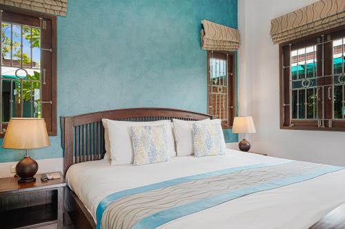 MyVillage Lamai في شاطئ لاماي: سرير في غرفة نوم بجدران زرقاء ونوافذ