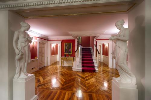 two statues in a hallway with a staircase at Villa Cora in Florence