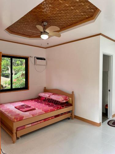 a bedroom with a bed with pink sheets and a ceiling at Ana's Bungalow in Siquijor