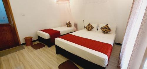 a room with two beds with red and white sheets at SMW Lodge Sigiriya in Sigiriya