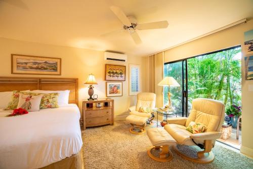 a bedroom with a bed and two chairs and a window at Wailea Ekahi 32B in Wailea