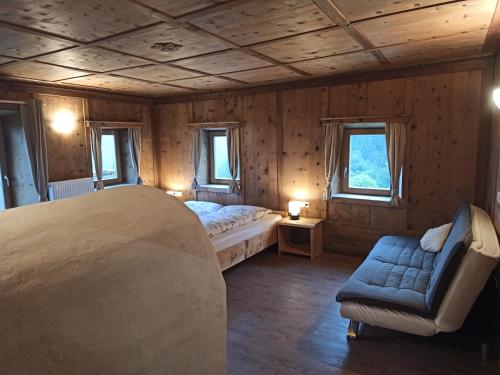 una camera con un letto e un divano e due finestre di Natur Appartments Riesen a San Lorenzo di Sebato