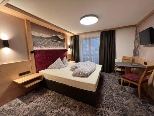 ein Hotelzimmer mit einem Bett und einem Tisch in der Unterkunft Jenneweinhof in Tux