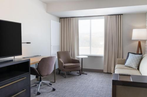 a hotel room with a television and a couch and chair at Residence Inn by Marriott Fairfield Napa in Fairfield